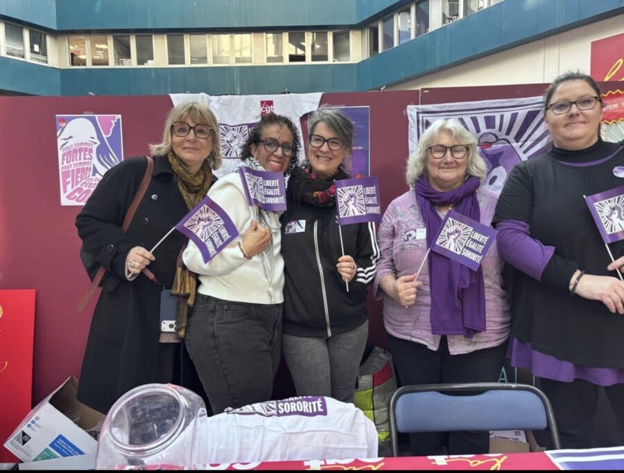 Photo avec 5 camarades femmes souriantes tenant des petits drpaeaux féminites avec les mentions "Liberté, égalité, sororité". 